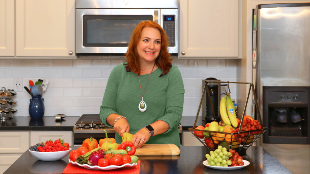 picture of woman in a kitchen with colorful vegetables.